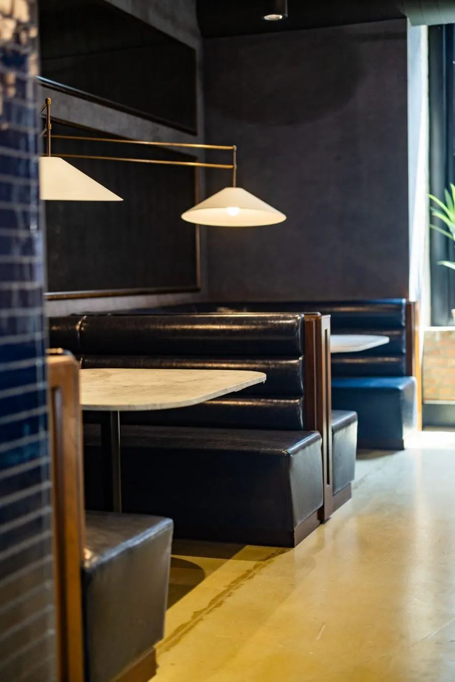 Navy leather banquette booths with marble tables and pendant lighting