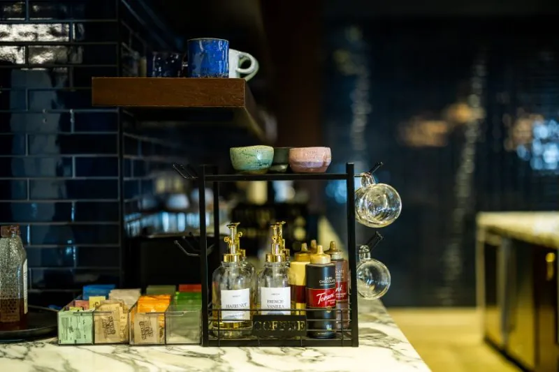 Coffee bar detail with ceramic mugs, syrups, and navy tile