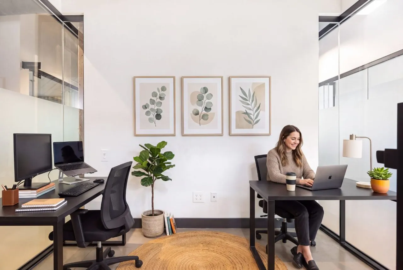 Polished two-desk private office with framed botanical prints and glass walls