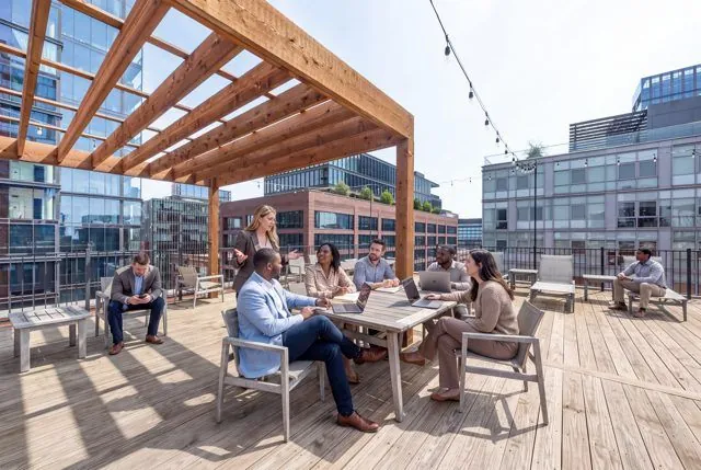 Team gathered around a table on the rooftop deck under the pergola, Fulton Market skyline beyond