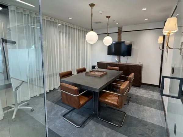Haymarket meeting room—upholstered chairs beneath brass globe pendants with display and glassboard