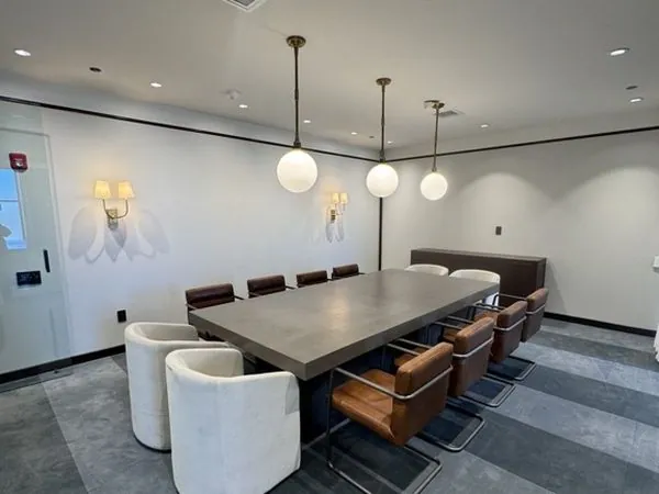 Howard meeting room—slip-covered chairs along a long concrete table with sheer curtains and glassboard