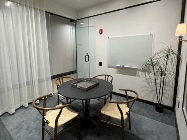 Richters meeting room—round black table with four wishbone chairs and a frosted glassboard