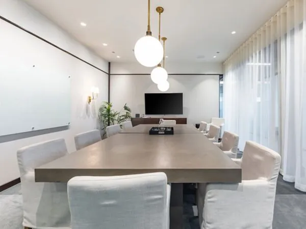 Sangamon meeting room—long concrete table with mixed leather and bouclé seating under three globe pendants