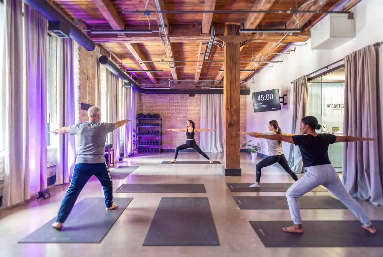 Members in a yoga class under timber ceilings in the wellness studio